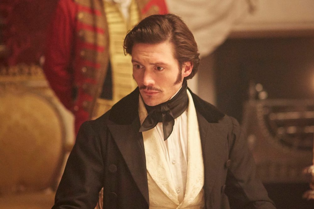 David as Prince Ernest in Victoria, in evening dress and a black silk cravat, with a footman in red livery behind him